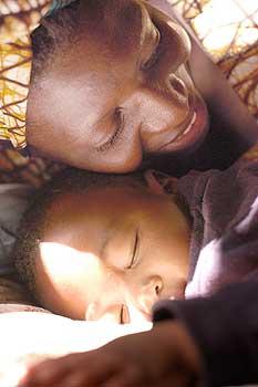 すやすや眠るわが子チョルウェちゃんにほおを寄せるルースさん＝ザンビア・ルサカで梅村直承写す